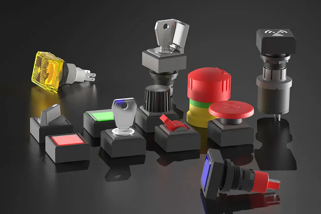 Not-Halt-Taster, quadratische Drucktasten, Schlüsselschalter und Wahlschalter auf einer schwarz-spiegelnden Oberfläche. Manche Taster liegen, andere stehen.