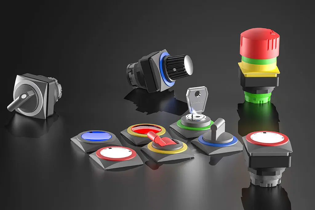 Not-Halt-Taster, quadratische Drucktasten, Schlüsselschalter und Wahlschalter auf einer schwarz-spiegelnden Oberfläche. Manche Taster liegen, andere stehen.