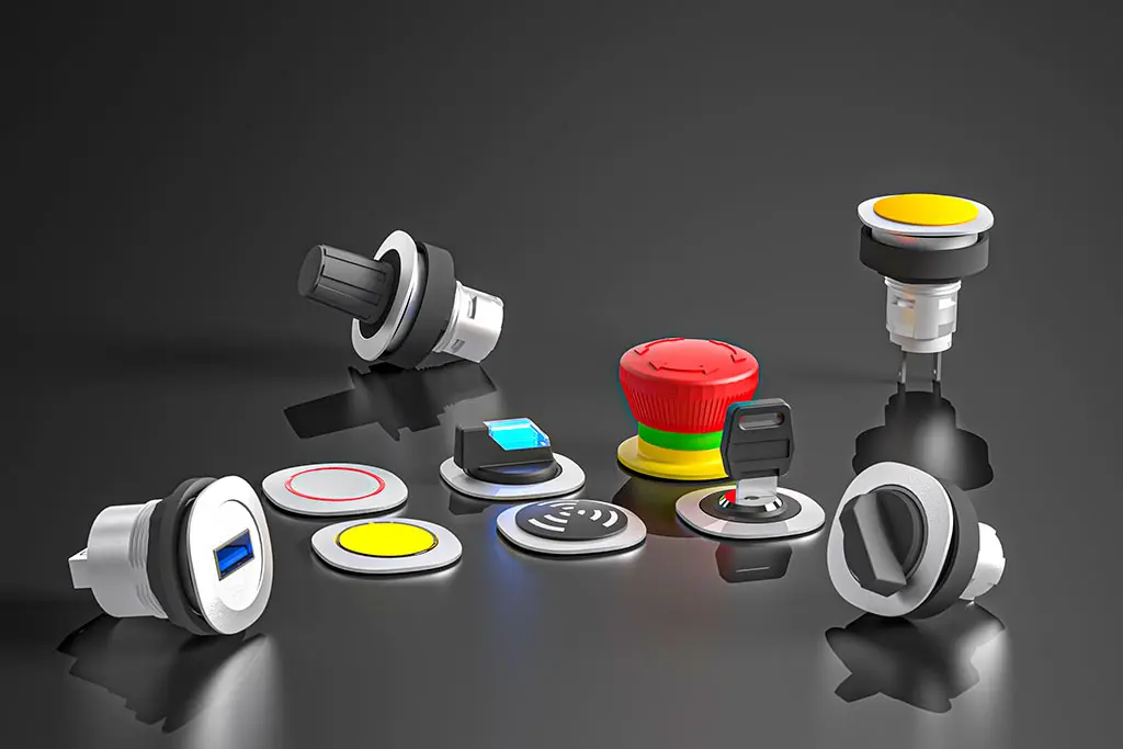 Not-Halt-Taster, USB-Buchsen, Drucktasten, Schlüsselschalter und Wahlschalter auf einer schwarz-spiegelnden Oberfläche. Manche Taster liegen, andere stehen.